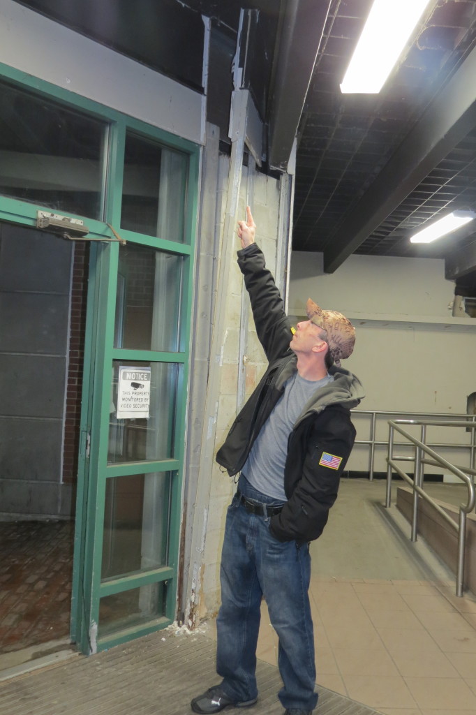 Museum Square resident Mike Thibideau points to open wires and falling concrete 