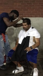 TMF Volunteer Jershawn Brown gives hair cuts to the homeless at the Buckley Garage in Lawrence during TMF family dinner 